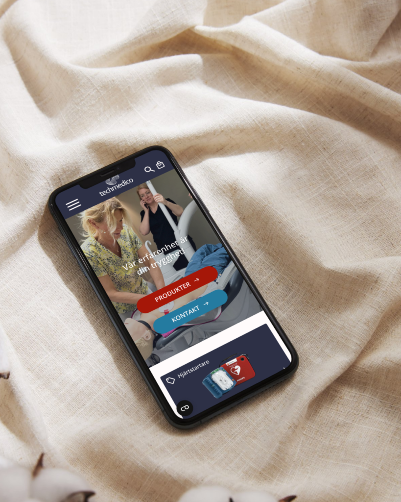 En smartphone som ligger på en soffa. Smartphonen visar startsidan av Techmedico