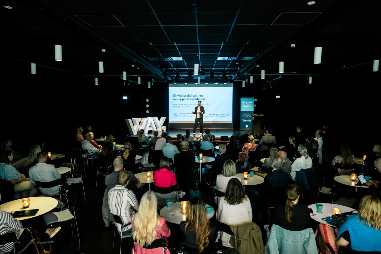 Erik Modig står på scen framför publik i Kristianstad på Show The WAY