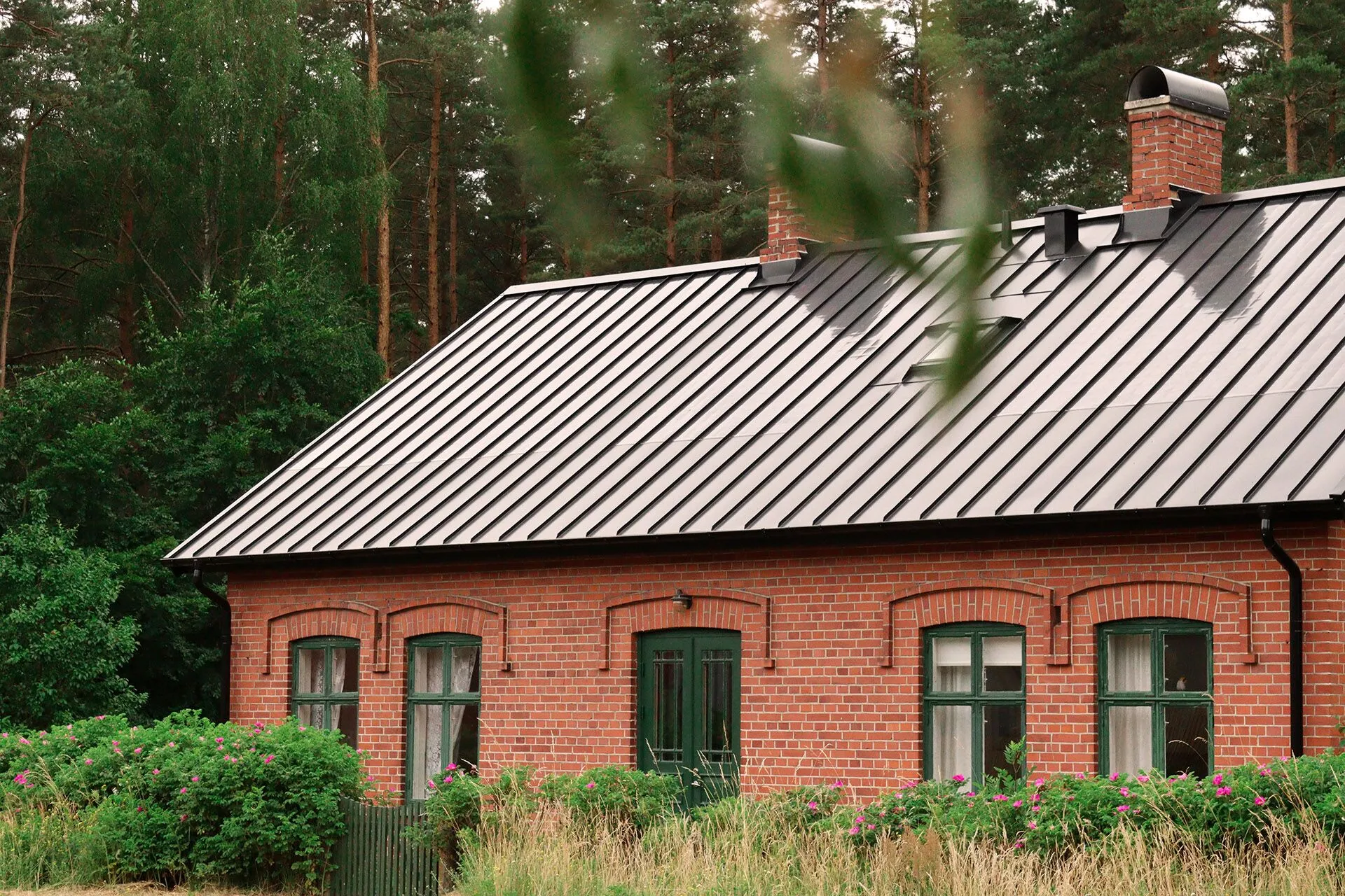 Bild på ett tegelhus i skogen med Midsummer diskreta solpaneler.