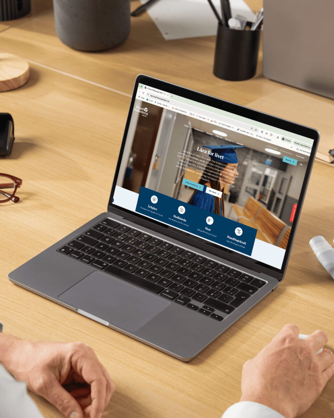 En person sitter vid en laptop. På laptopens skärm ser man Raoul Wallenbergs nya startsida