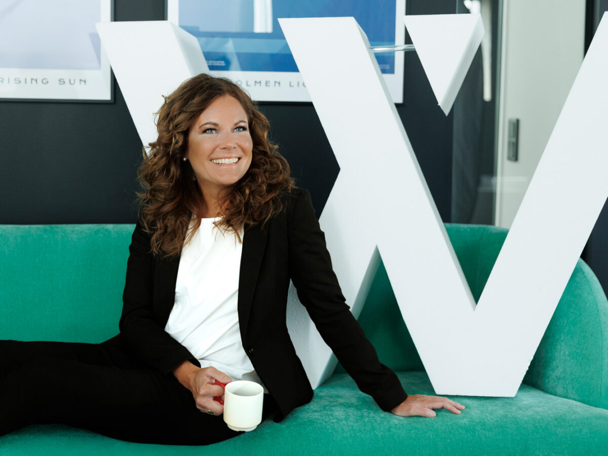 Annette sitter i en grön soffa tillsammans med ett stort W i frigolit