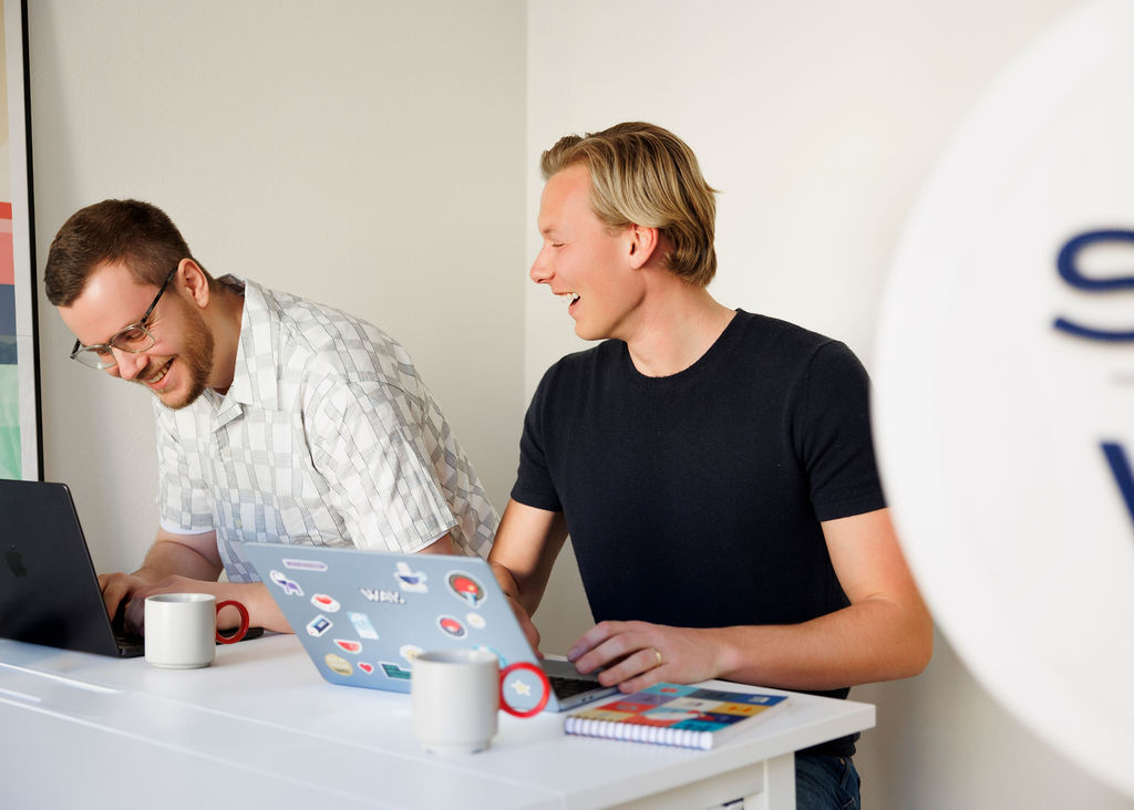David ocha Pierre sitter tillsammans med sina laptops och skrattar.